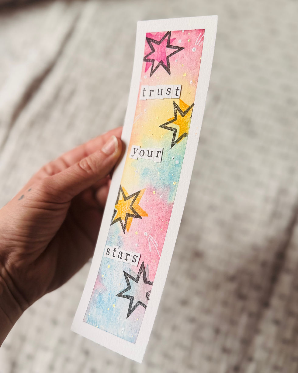 Lesezeichen "trust your stars" - von einer Hand in die Kamera gehalten, leicht schräge Ansicht