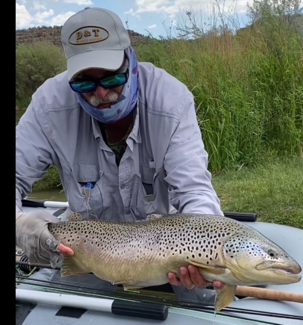 An angler showing off a massive Brown Trout while fishing on his Dave Scadden inflatable fishing pontoon boat.