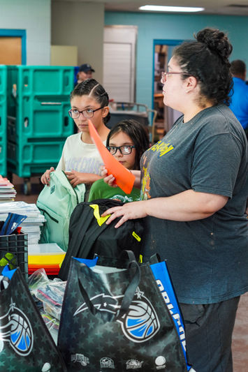 Child receiving a backpack and gift card at The Greatest Commandment Inc. Back-to-School Outreach in Orlando 2024.