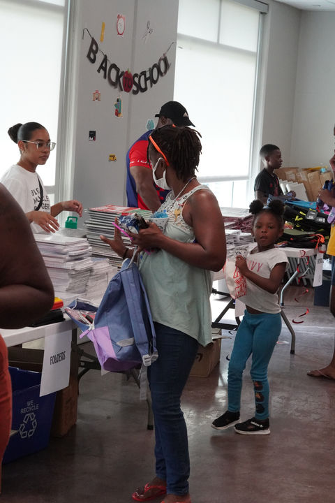 Child receiving a backpack and gift card at The Greatest Commandment Inc. Back-to-School Outreach in Orlando 2024.