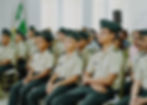 Niños en uniformes militares sentados en sillas, Colegio Militar Acoolsure, atención y enfoque.