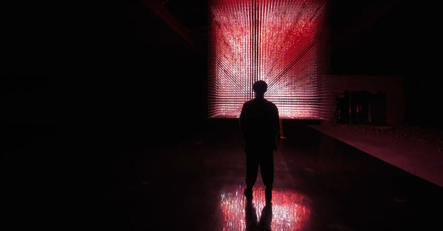 Sho Ikushima standing in front of the light sculpture of flames exhibit on the Sauna Channel episode: TeamLab Mifuneyama in Rakuen Park, Japan.