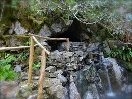 An image of Goldmyer Hot Springs in North Bend, Washington, USA from Sauna Channel shows a stacked rock formation and a small waterfall forming the natural geothermal hot springs in an old growth forest several miles from the nearest trailhead