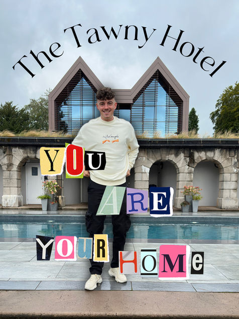 A person stands in front of a modern building with a pool, framed by stone arches and greenery. Above the person, curved text reads “The Tawny Hotel.” Overlaid on the image in colorful, cut-out letters is the phrase: “YOU ARE YOUR HOME.” The person is dressed casually in a light sweatshirt and dark pants, with white sneakers. The setting appears tranquil and inviting, blending contemporary architecture with natural surroundings.