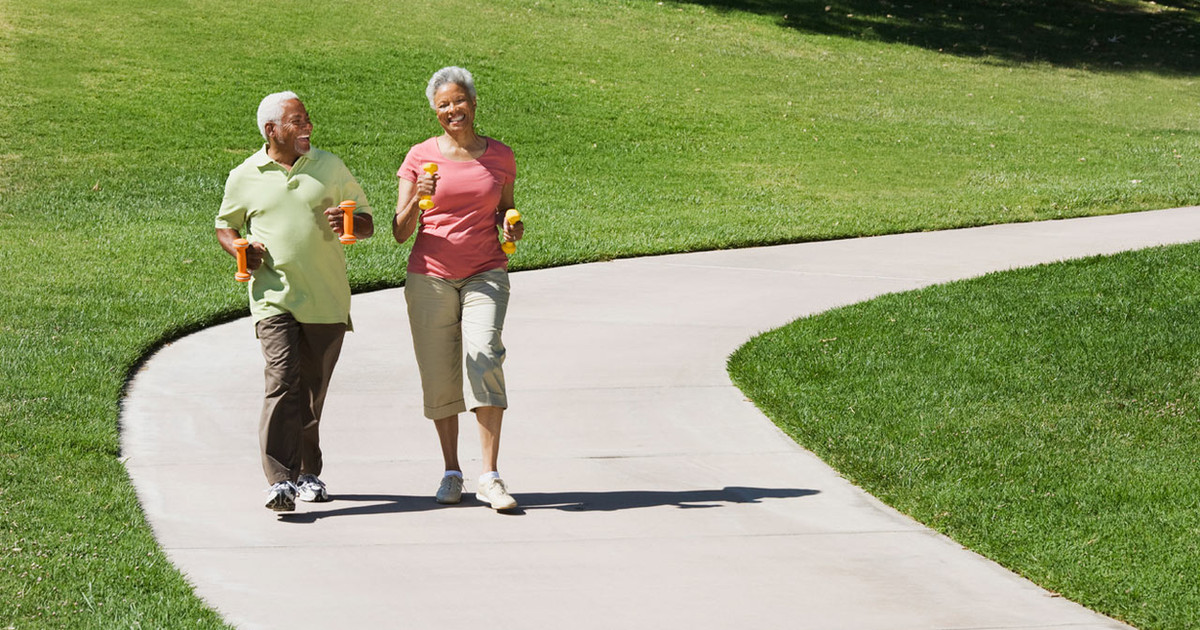 A person walking confidently through a local park, demonstrating how regular movement supports recovery from persistent pain.