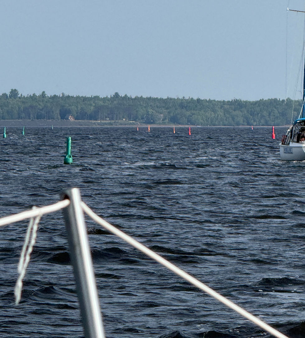Sailboat facing a series of channel markers.