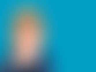 Young child with messy hair, wearing red glasses and a blue suit, holding face with a surprised expression against a teal background.