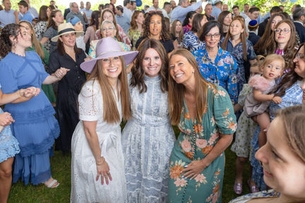 a group of women posing for a picture with one wearing a purple hat