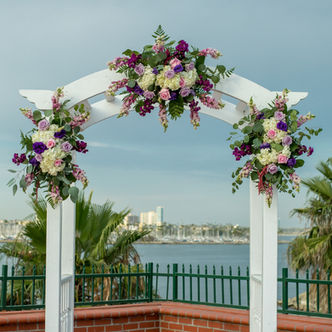 White wedding arch decorated with purple and white flowers