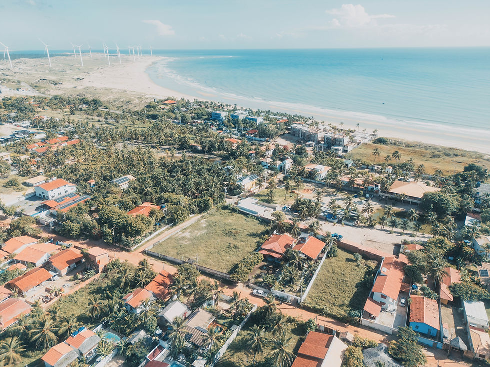 Vista aérea da vila de Icaraí de Amontada, Ceará, com a Pousada Brisa Del Mar em destaque entre as casas e a vegetação litorânea, à beira da praia de mar azul e areia clara.