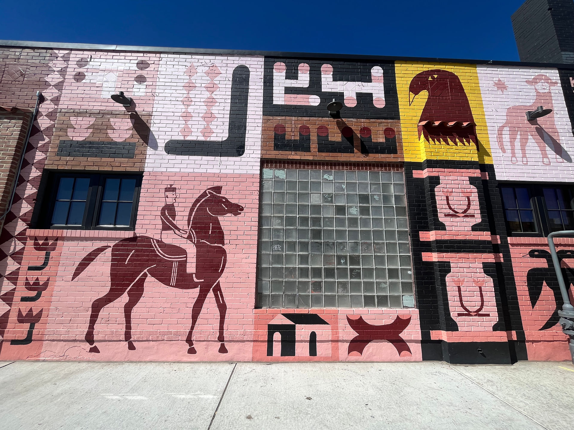 Close up of artwork on front of Corsica Wine Bar building with glass cutout in wall