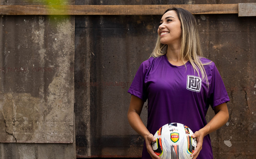 Kelen segura uma bola de futebol enquanto olha para o lado