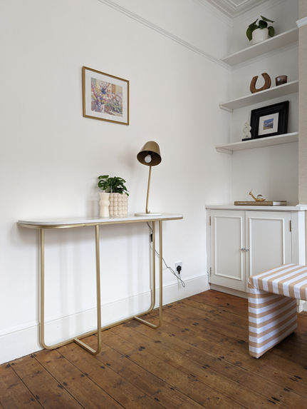 Slim brass console table with desk lamp and built-in alcove shelving.