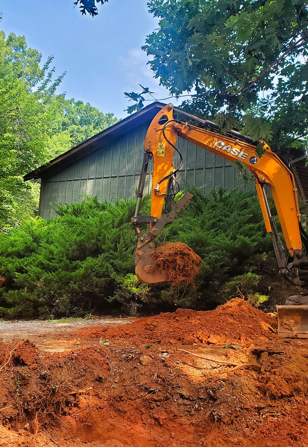Yellow Case excavator digging red soil near a green building