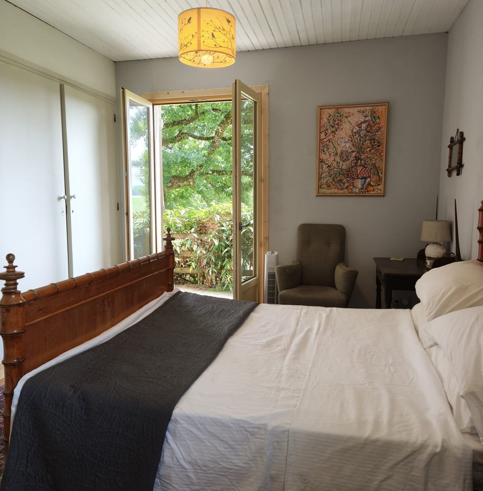Spacious bedroom with balcony and garden views in a renovated farmhouse holiday rental in Southwest France.