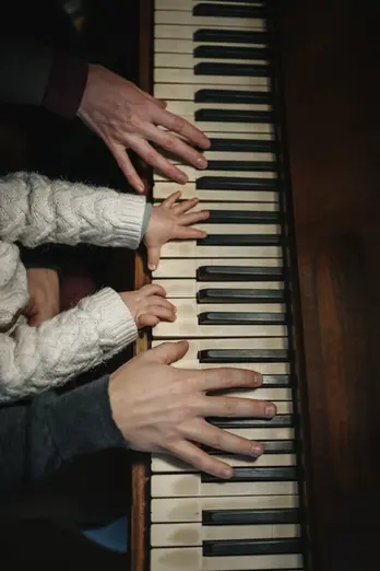 Détails de mains jouant du piano durant une séance photo lifestyle à la maison