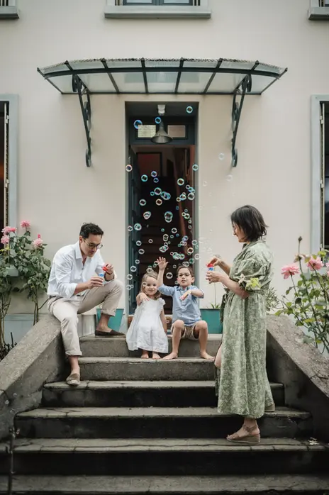 Portrait poétique de famille devant leur maison au cours d'une séance photo lifestyle en Essonne