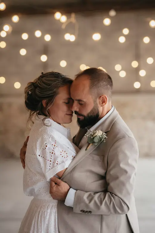 Couple de mariés enlacés, guirlande lumineuse donnant l'impression qu'ils sont entourés d'étoiles