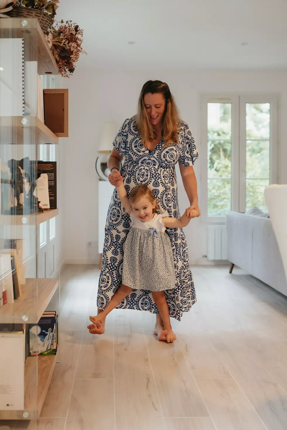 jeu candide d'une mère faisant marcher sa petite fille sur ses pieds durant une séance photo en Essonne