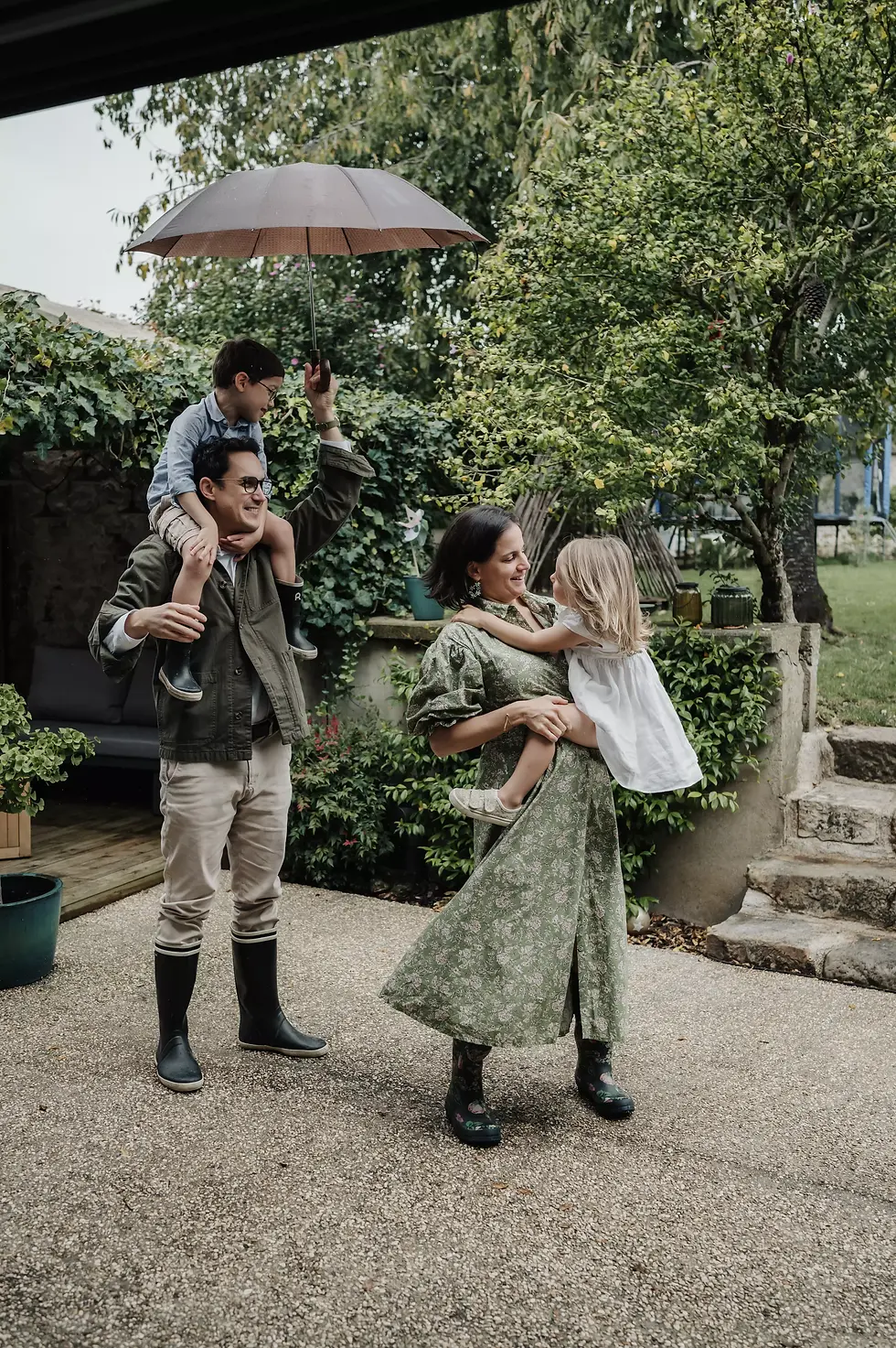 Parents jouant avec leurs enfants sous la pluie pendant une séance photo à la maison