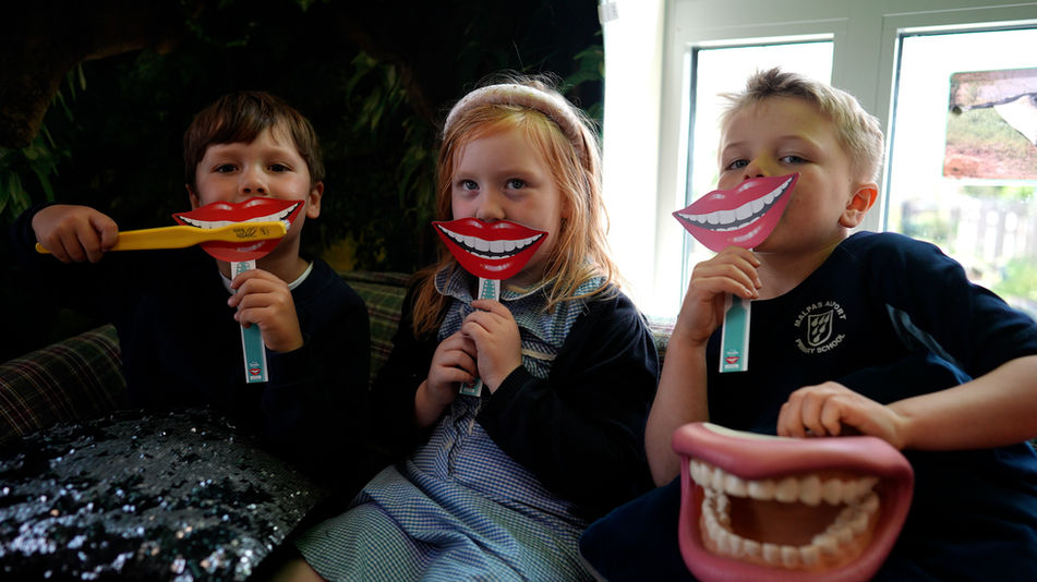 supervised toothbrushing - 3 children sat with big smiling mouth cards