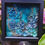 Thumbnail: Framed hand made coral reef wall art. Sculptural 3D clay coral reef in shimmery blue tones depicting a coral reef.