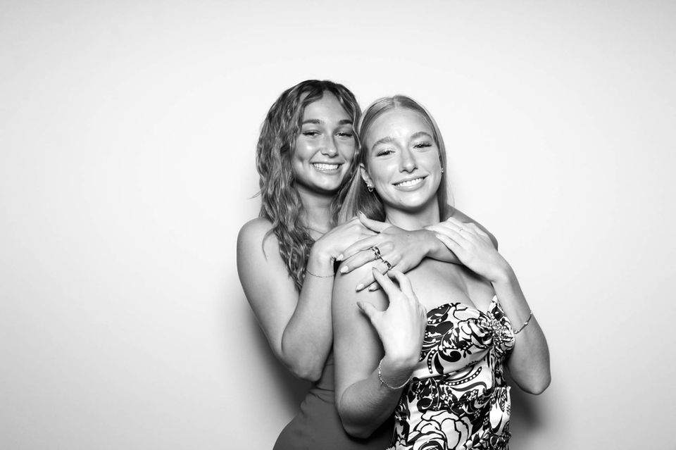 Two smiling women embrace at a photo booth
