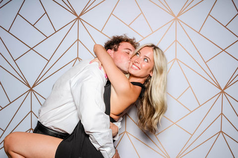 Couple embraces in photo booth with geometric backdrop