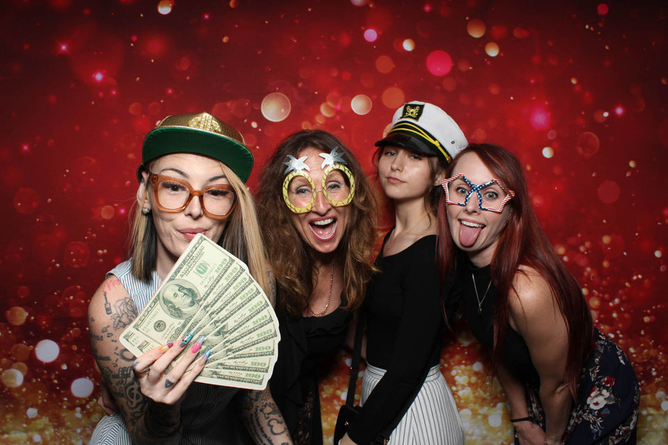 Four women in funny hats and glasses at a photo booth