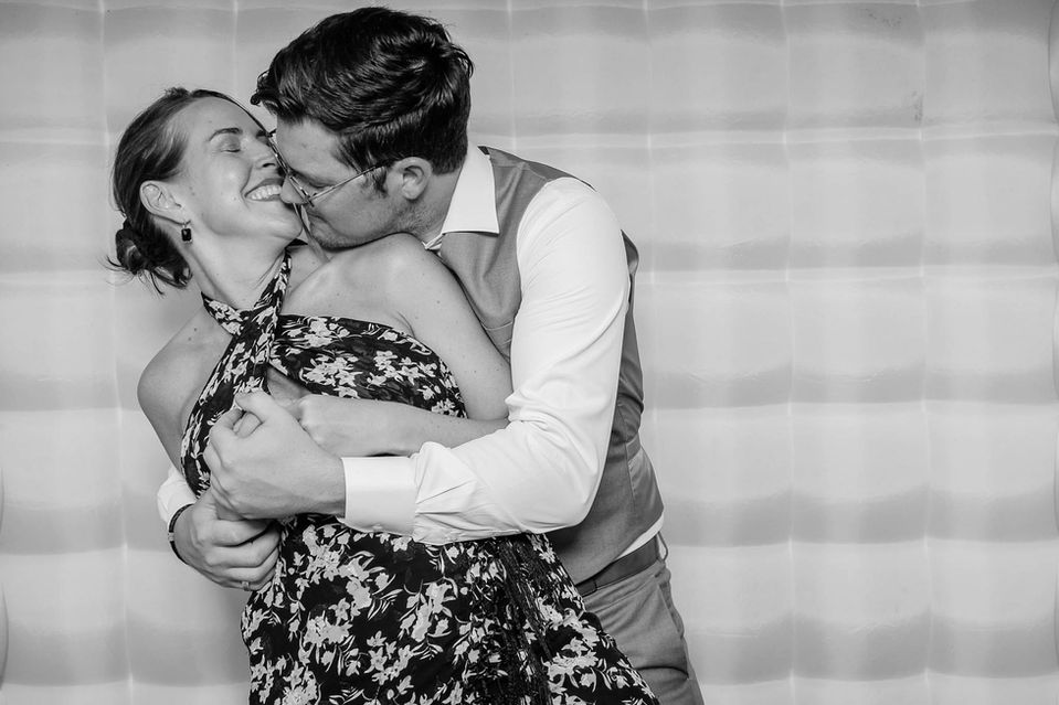 Happy couple sharing a passionate kiss at a photo booth.