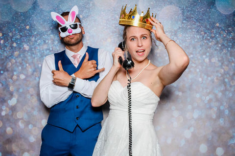 Bride and groom in photo booth, playful masks and phone