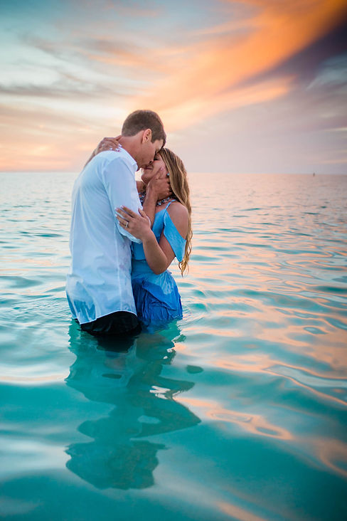 Romantic couple posing in the water for engagement sunset photo session at North Jetty Beach in Nokomis, FL