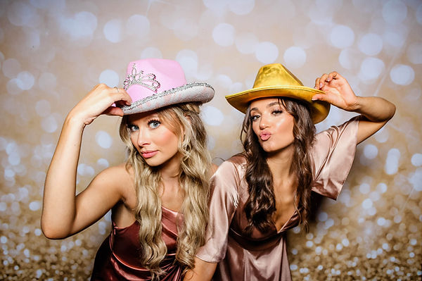 2 girls posing with hats in an open air photo booth