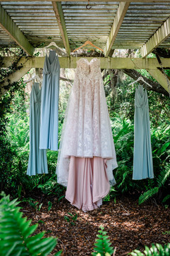 bride and bridesmaids dresses hung amoung the ferns at chapel creek weddings and events