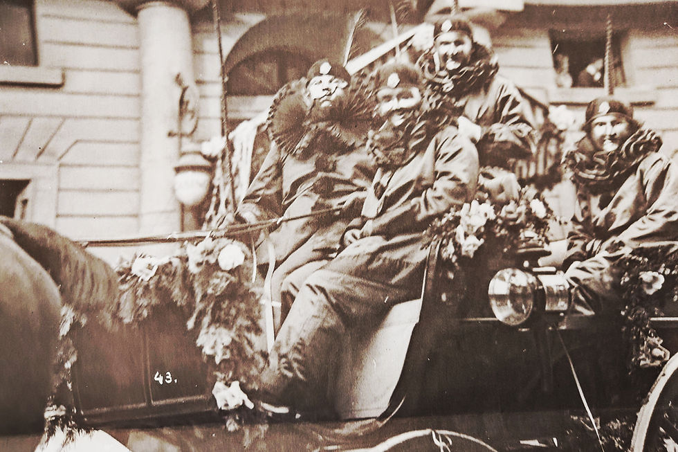Ein Foto einer Chaise an der Basler Fasnacht 1925. Zu sehen sind vier Fasnächtler in Pierrot Larven und Kostümen.