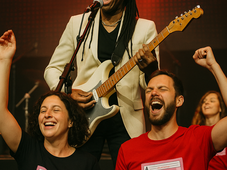 Nile Rodgers performing live on stage with electric guitar, joined by enthusiastic fans in retro cassette tape T-shirts.