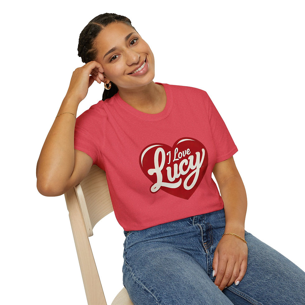 Woman sitting on a stool wearing a red “I Love Lucy” T-shirt and jeans, smiling with hand resting on her face.