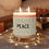 Thumbnail: Lit Peace Candle surrounded by glowing fairy lights on a wooden surface.