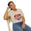 Thumbnail: Woman seated and smiling in a beige “I Love Lucy” T-shirt and jeans.