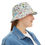 Thumbnail: Woman wearing a white bucket hat with colorful doodle-style prints, styled with a denim jacket and white t-shirt, smiling sli
