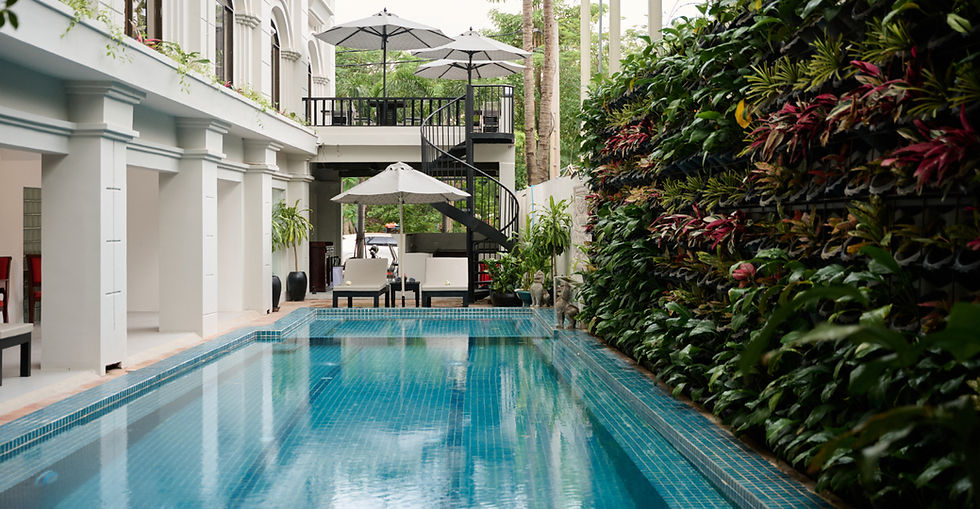 Outdoor lap pool beside a vertical garden wall and balcony.