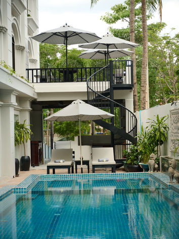 Outdoor pool with lounge chairs and spiral staircase.