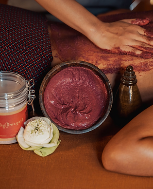 Spa therapist applying red body scrub to a client's back