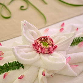 White towel folded like a flower with a pink lotus floral center