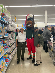 Rosie Rivera in uniform standing with the Sheriff’s Office community mascot, Lightning the moose, and a Sheriff’s Office deputy at the annual Shopping with a Shield event.