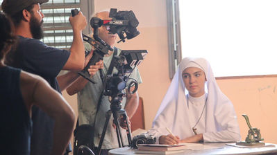 Set de filmagem com atriz vestida de freira e câmera