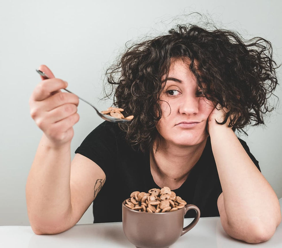 Femme fatiguée mangeant automatiquement des céréales, illustrant les envies alimentaires liées à la fatigue mentale