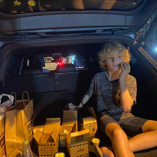 Sebastian in open trunk of car with takeout bags