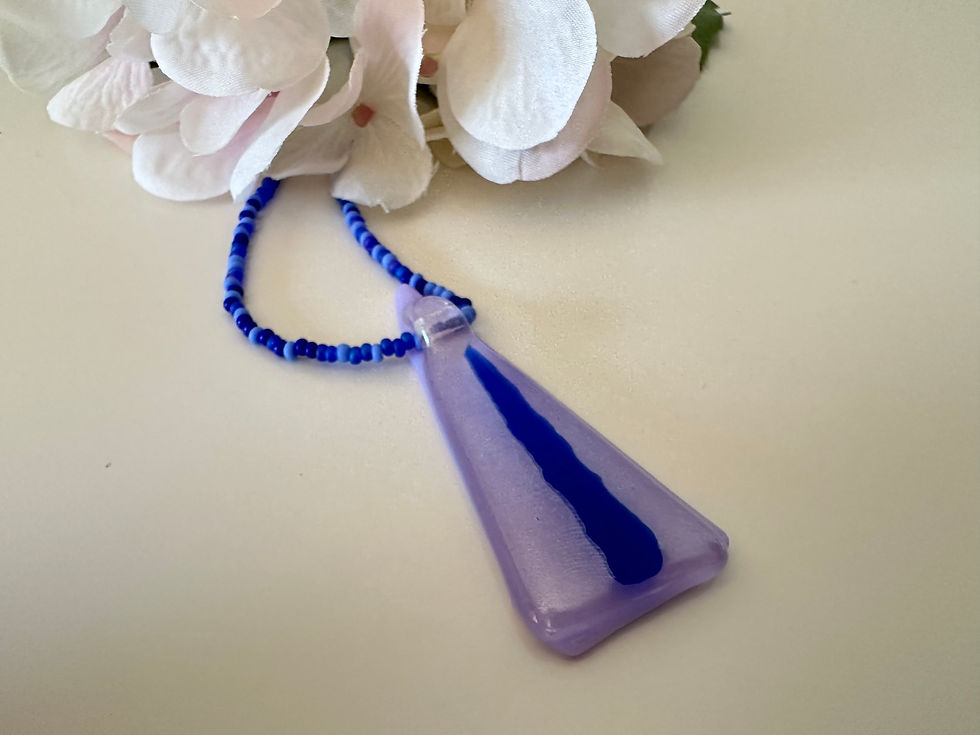 Miniaturbild: Detailansicht eines lila-blauen Glasanhängers neben einer weißen Hortensienblüte.