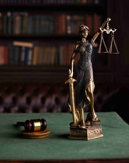 Estatua de la Justicia sosteniendo una balanza junto a un mazo de juez en una biblioteca jurídica, representando el derecho sucesorio y la administración patrimonial en Florida